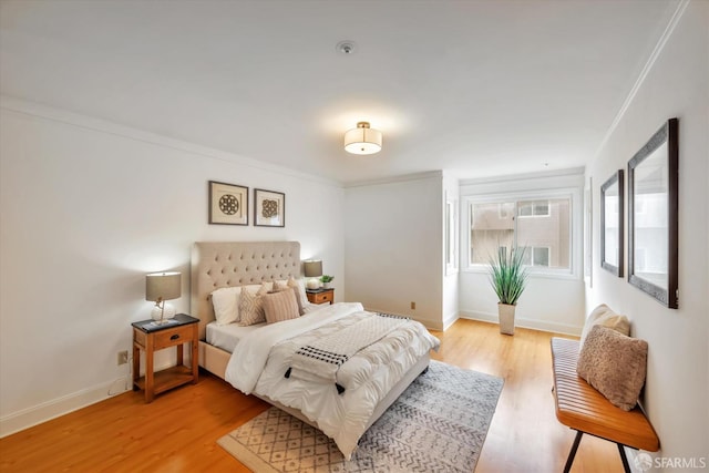 bedroom with ornamental molding, light wood-style flooring, and baseboards