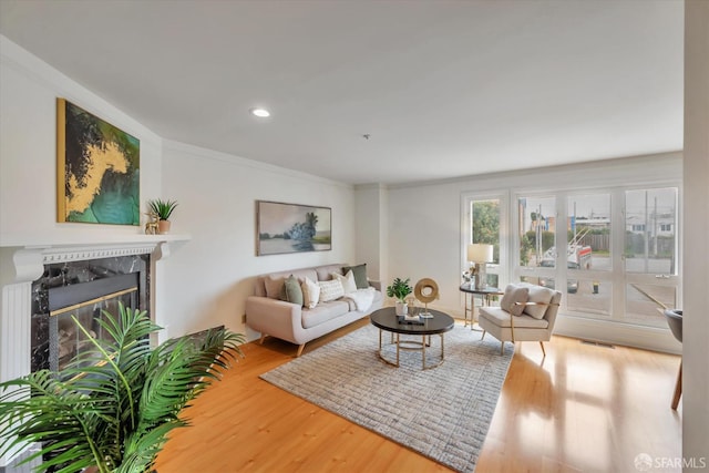 living area featuring recessed lighting, wood finished floors, a high end fireplace, and crown molding