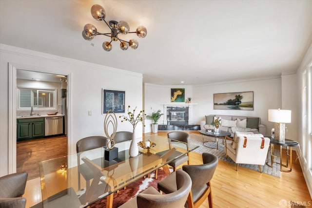 dining area with light wood-style floors, a premium fireplace, and ornamental molding