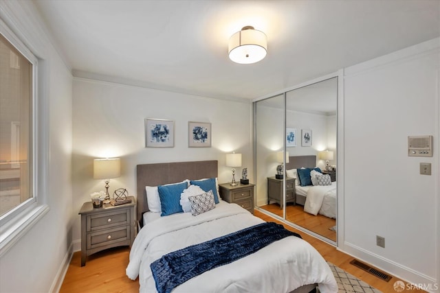 bedroom featuring a closet, visible vents, light wood-style flooring, and baseboards