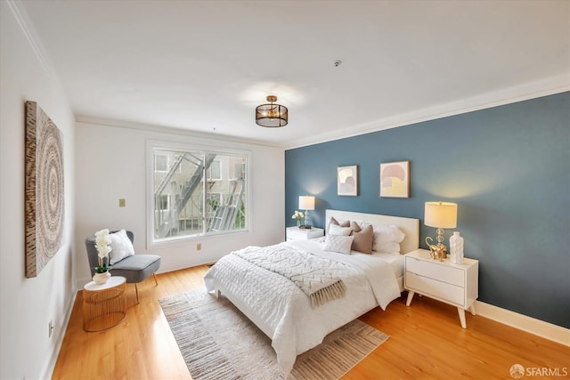 bedroom featuring light wood-type flooring, baseboards, and crown molding