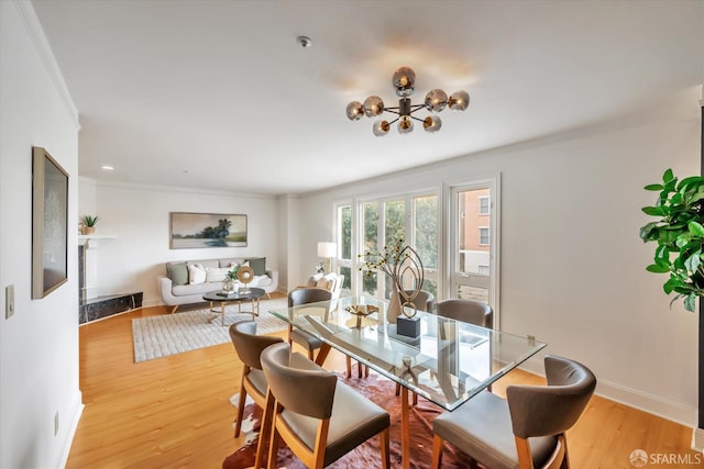 dining area featuring baseboards, light wood finished floors, crown molding, and a notable chandelier