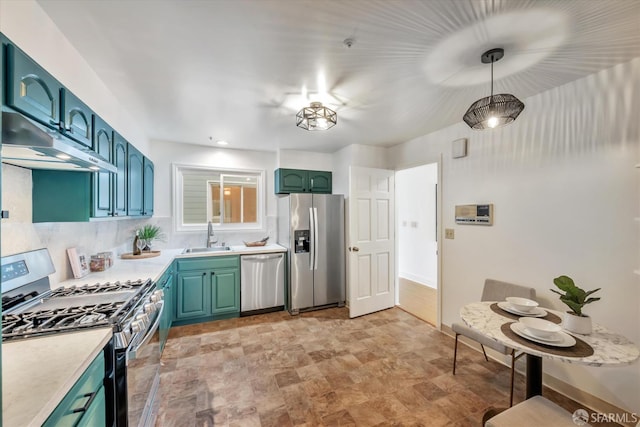 kitchen with light countertops, hanging light fixtures, appliances with stainless steel finishes, a sink, and under cabinet range hood