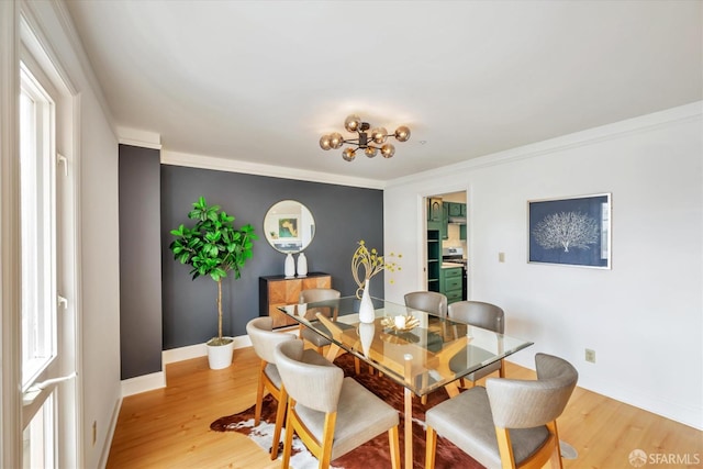 dining space with ornamental molding, light wood-type flooring, and baseboards