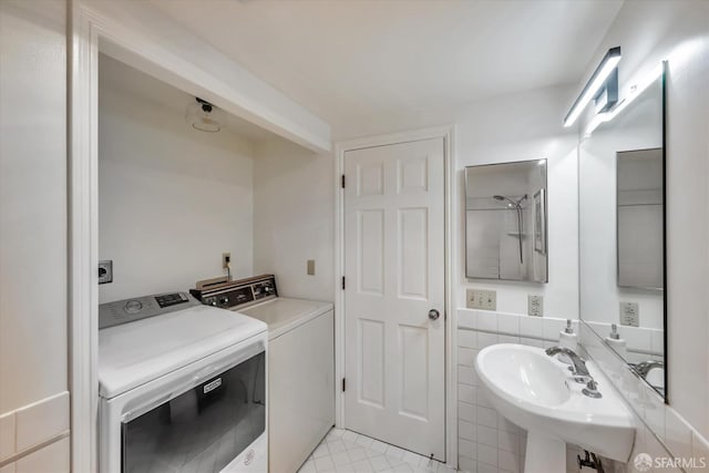 bathroom with independent washer and dryer, a sink, and tile patterned floors