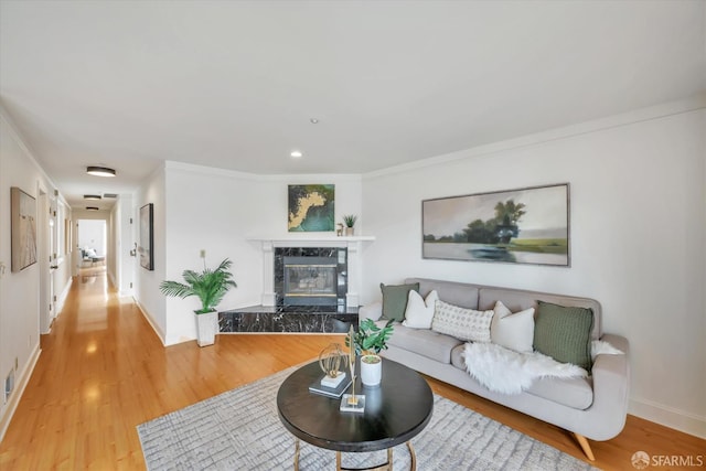 living area with light wood finished floors, baseboards, a premium fireplace, ornamental molding, and recessed lighting