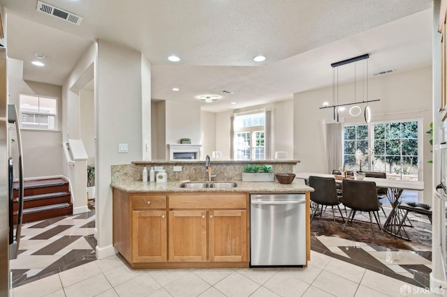 kitchen featuring light stone countertops, sink, hanging light fixtures, light tile patterned floors, and stainless steel dishwasher