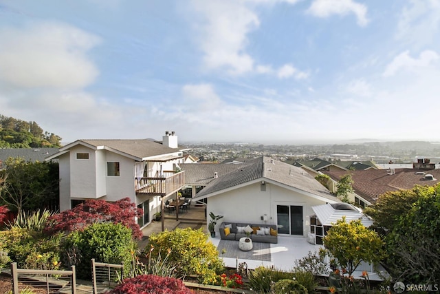 back of house with an outdoor living space, a patio area, a balcony, a shingled roof, and stucco siding
