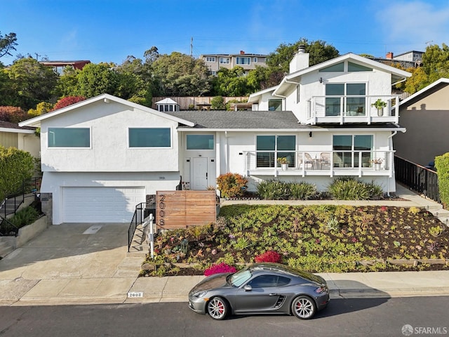 view of front facade featuring an attached garage, a balcony, concrete driveway, and stucco siding