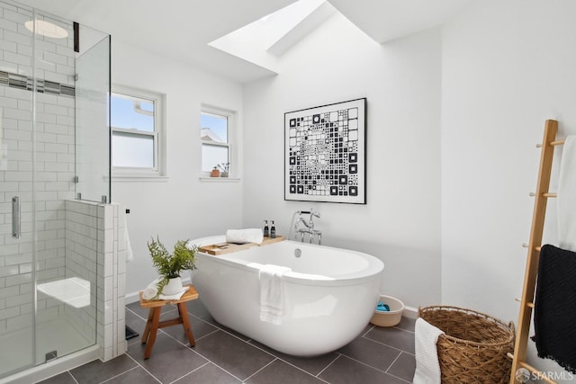 bathroom featuring a shower stall, a freestanding bath, baseboards, and a skylight