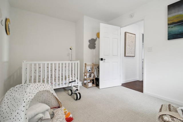 carpeted bedroom featuring baseboards and a nursery area