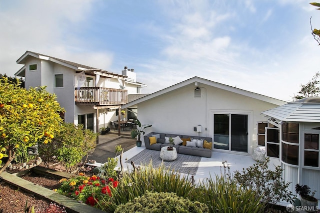back of house featuring stucco siding, a balcony, an outdoor living space, and a patio