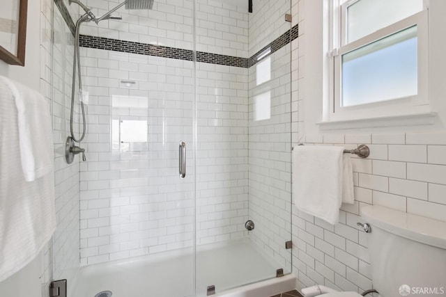 full bathroom featuring a shower stall, toilet, and tile walls