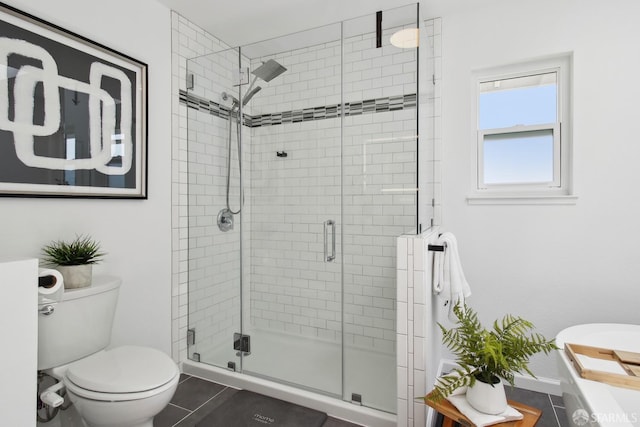 bathroom with a shower stall, toilet, baseboards, and tile patterned floors