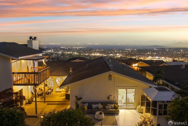 back of property at dusk with outdoor lounge area, a patio area, and stucco siding