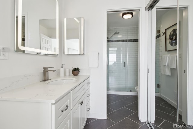 bathroom featuring toilet, a stall shower, vanity, baseboards, and tile patterned flooring
