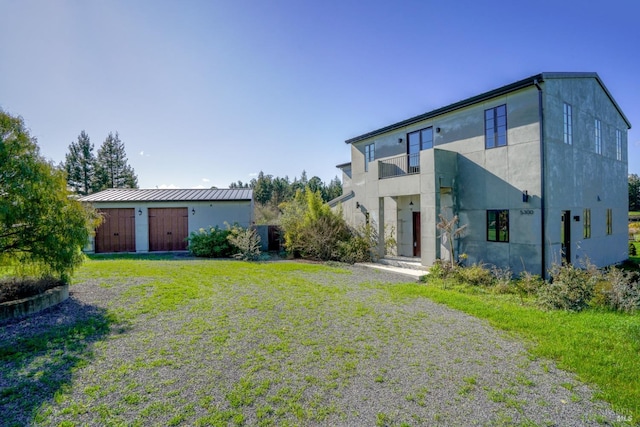 back of house with a lawn and a balcony