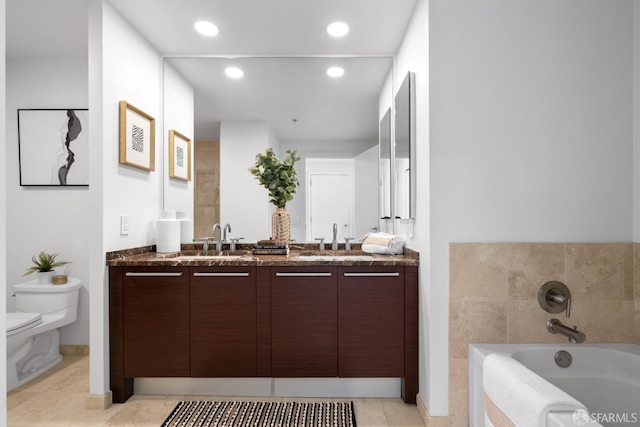 bathroom featuring a garden tub, a sink, double vanity, and toilet
