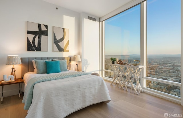 bedroom with floor to ceiling windows, wood finished floors, and visible vents