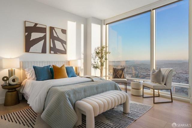 bedroom with expansive windows and wood finished floors