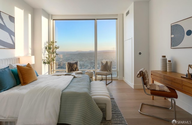 bedroom with baseboards, multiple windows, wood finished floors, and visible vents