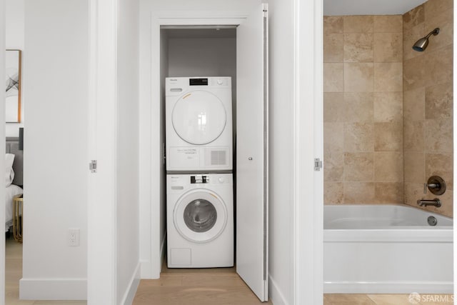 laundry area featuring stacked washer and clothes dryer, light wood-style flooring, and laundry area