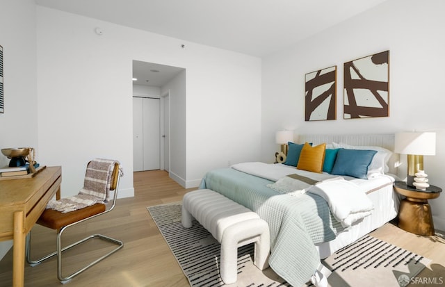 bedroom featuring baseboards, wood finished floors, and a closet