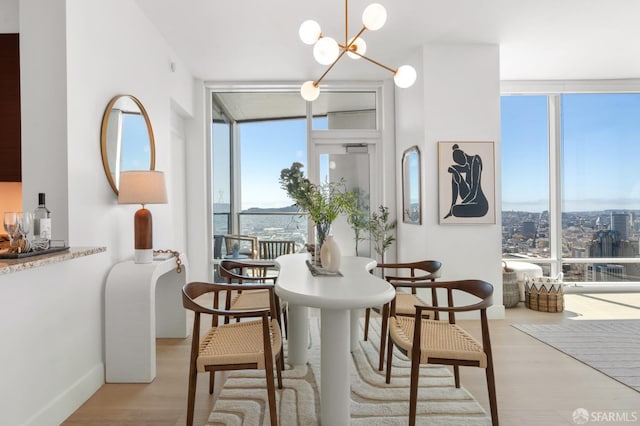 dining room featuring an inviting chandelier, expansive windows, and light wood-type flooring