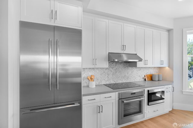 38 Steiner St Unit 303, San Francisco, CA 94114 - kitchen with built in appliances, under cabinet range hood, tasteful backsplash, white cabinets, and light wood-style floors
