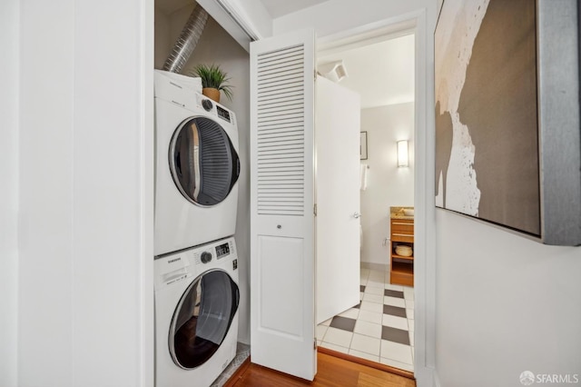 washroom with hardwood / wood-style floors and stacked washer / drying machine