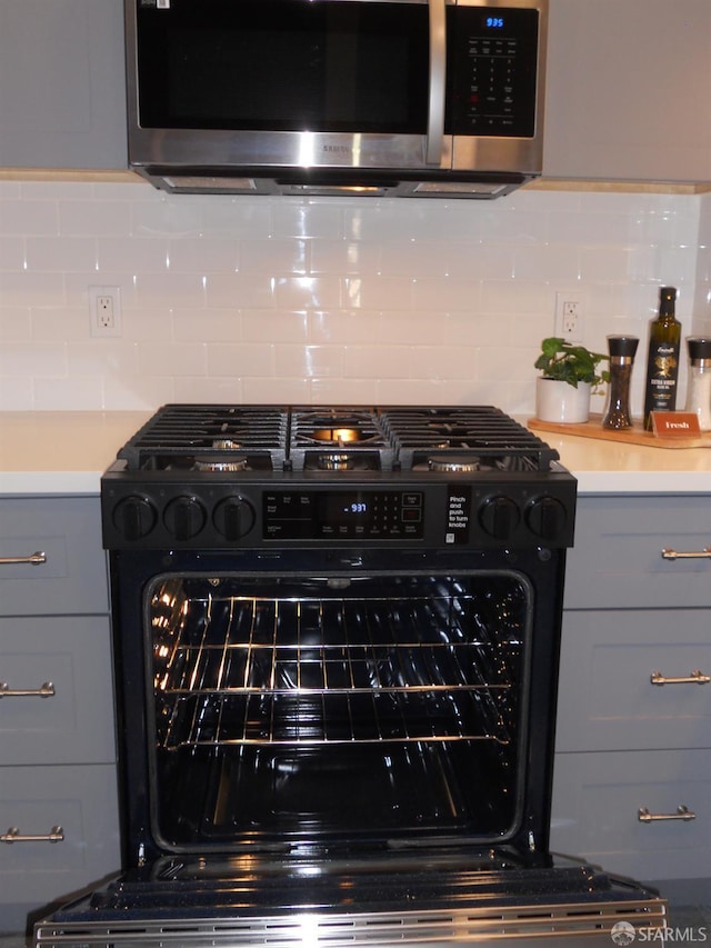 700 12th Ave Unit 2, San Francisco, CA 94118 - kitchen view of stainless steel microwave, black gas stove, gray cabinets, decorative backsplash, and light countertops