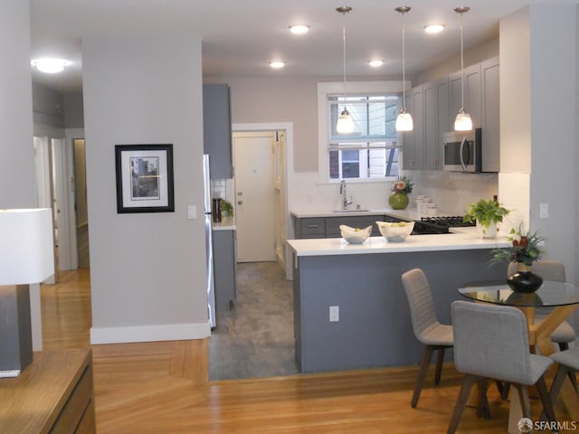 700 12th Ave Unit 2, San Francisco, CA 94118 - kitchen with stainless steel microwave, a peninsula, tasteful backsplash, light countertops, and recessed lighting