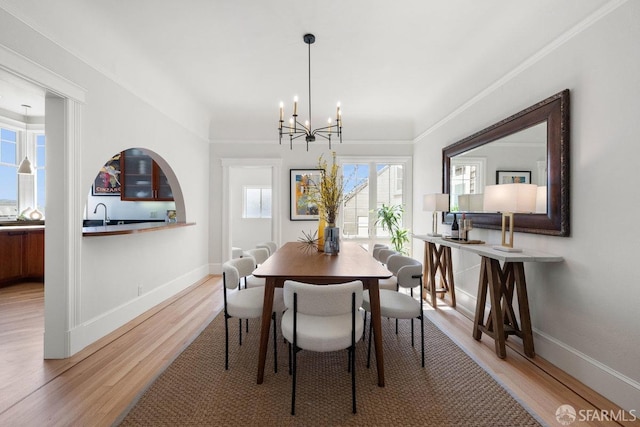 dining area featuring ornamental molding, light wood-type flooring, a notable chandelier, and baseboards