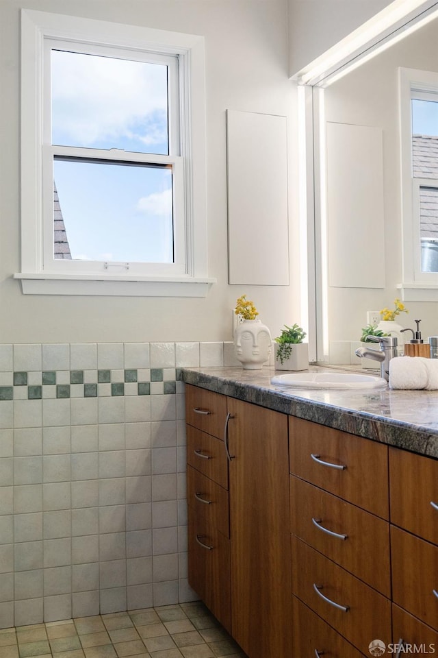 bathroom with tile patterned flooring, vanity, tile walls, and a healthy amount of sunlight