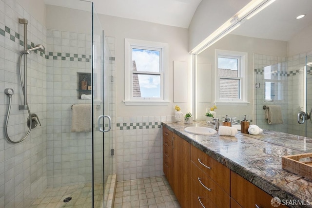 full bathroom with vaulted ceiling, a stall shower, vanity, and tile patterned floors