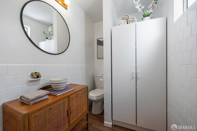 full bathroom featuring a wainscoted wall, tile walls, toilet, vanity, and wood finished floors