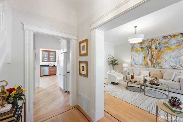 corridor featuring visible vents, crown molding, and light wood finished floors