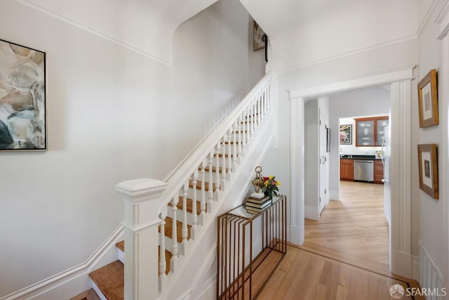 stairway with a towering ceiling, baseboards, visible vents, and wood finished floors