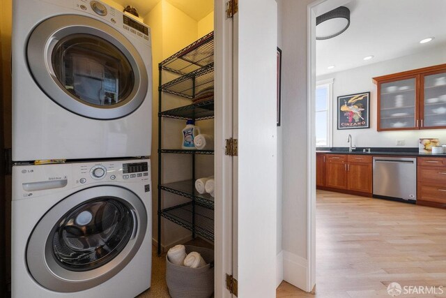 washroom featuring laundry area, light wood-style flooring, stacked washer / drying machine, a sink, and recessed lighting