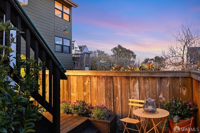 deck at dusk featuring stairs and fence