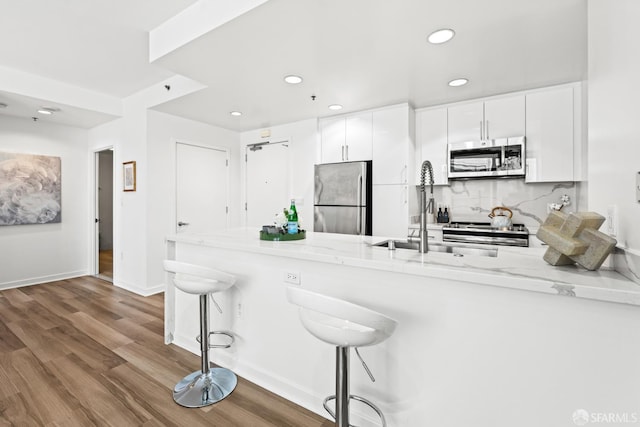 250 King St Unit 536, San Francisco, CA 94107 - kitchen with appliances with stainless steel finishes, a peninsula, recessed lighting, wood finished floors, and a breakfast bar