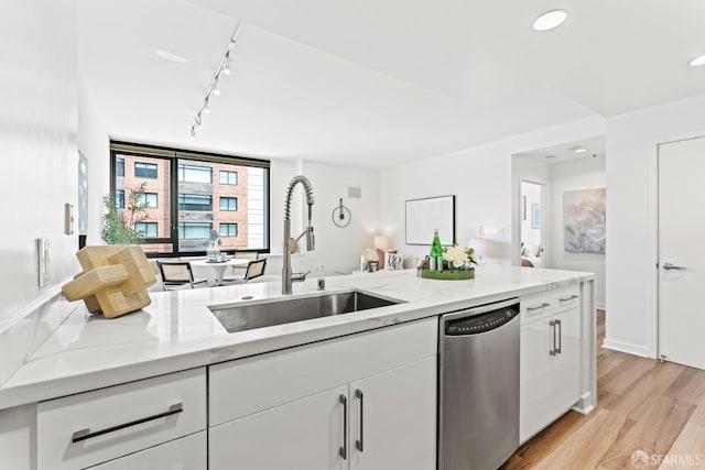 250 King St Unit 536, San Francisco, CA 94107 - kitchen featuring stainless steel dishwasher, white cabinetry, light wood-type flooring, track lighting, and light stone countertops