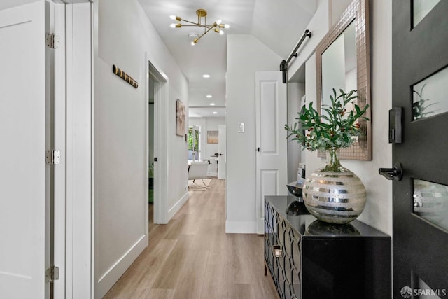 hall featuring a notable chandelier, baseboards, recessed lighting, light wood-style flooring, and a barn door