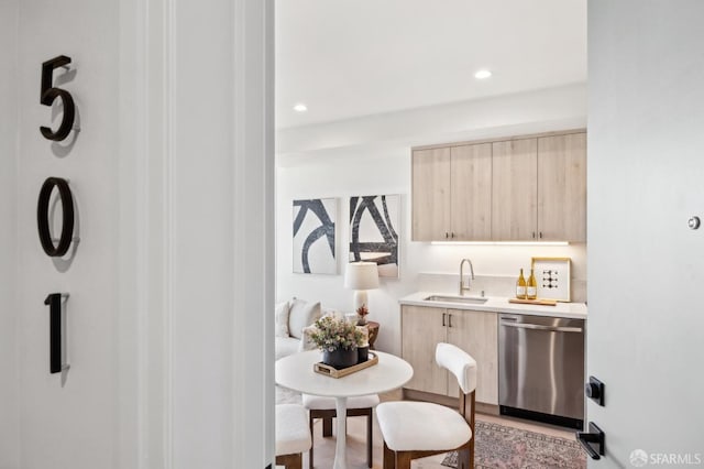 kitchen with light brown cabinetry, sink, and dishwasher