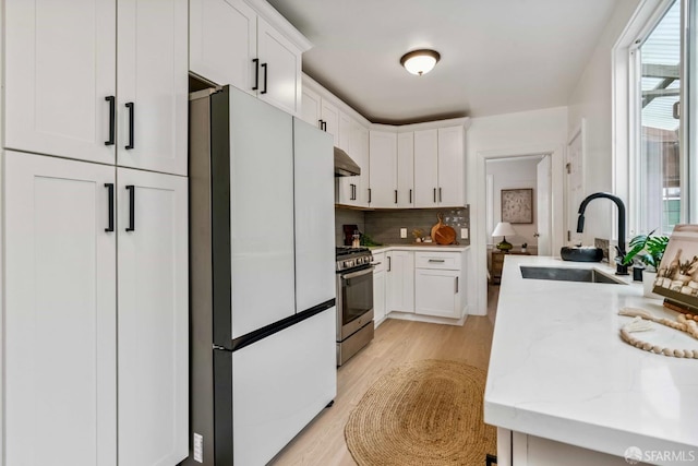 1210 40th Ave, San Francisco, CA 94122 - kitchen with freestanding refrigerator, gas stove, light wood-style floors, and backsplash