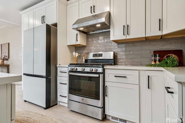 1210 40th Ave, San Francisco, CA 94122 - kitchen featuring under cabinet range hood, stainless steel gas range, freestanding refrigerator, light wood-type flooring, and light countertops