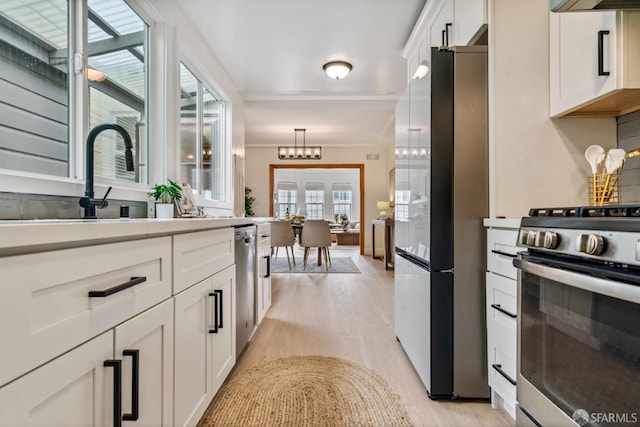 1210 40th Ave, San Francisco, CA 94122 - kitchen with stainless steel appliances, light wood-style flooring, white cabinetry, light countertops, and a chandelier