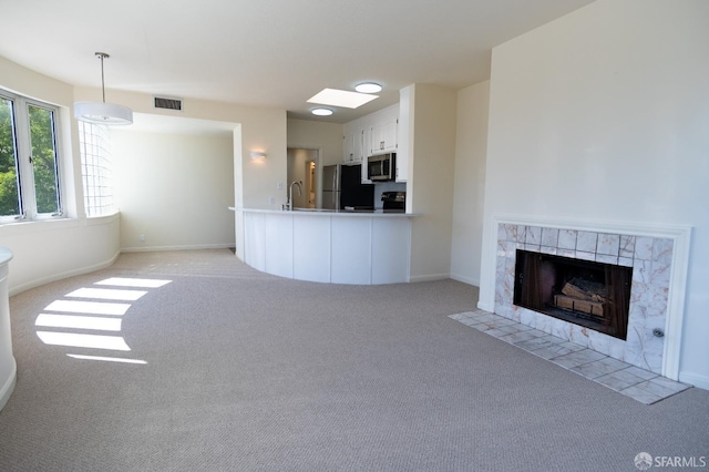 unfurnished living room with baseboards, a fireplace, light colored carpet, and a sink