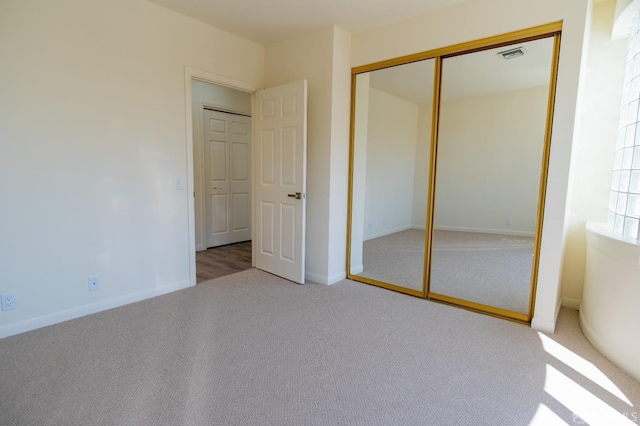 unfurnished bedroom featuring carpet floors, baseboards, a closet, and visible vents
