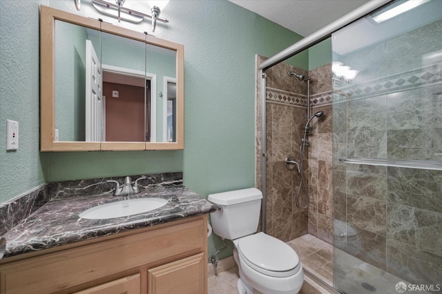 bathroom with toilet, vanity, a textured ceiling, and a shower with door